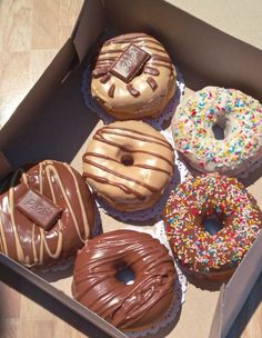 six donuts with chocolate frosting and sprinkles are in a box