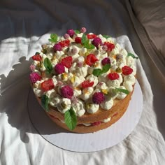 a cake that is sitting on top of a white plate with berries and mint leaves