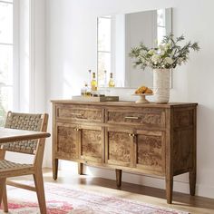 a wooden dresser sitting on top of a hard wood floor next to a table and chair