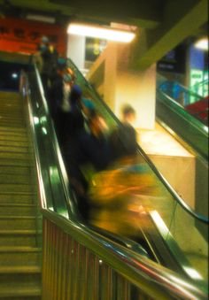 people riding down an escalator with their luggage on the bottom handrails