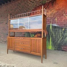 a large wooden dresser sitting next to a brick wall