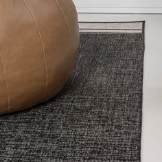 a brown leather bean bag sitting on top of a rug