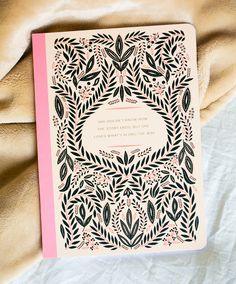 a pink and black wedding card with an intricate design on the front, surrounded by leaves