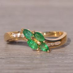 an image of two rings with green and white stones on them sitting on a wooden surface