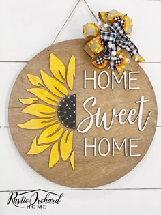 a wooden sign that says home sweet home with a sunflower on it and a bow