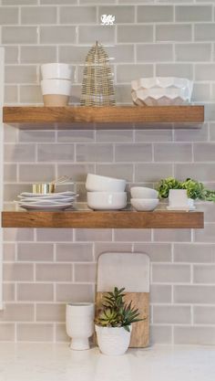 two wooden shelves filled with bowls and plates on top of white counter tops next to each other