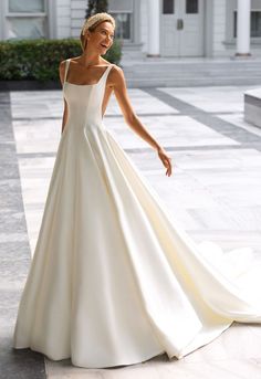 a woman in a white wedding dress posing for the camera with her hand on her hip