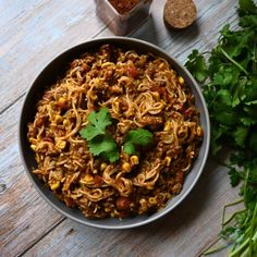 a bowl filled with noodles and garnished with cilantro on the side