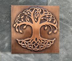 a metal plaque with a tree on it's face and roots in the center