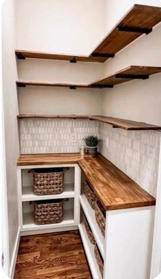 an empty walk in closet with wooden shelves and baskets on the bottom shelf next to it