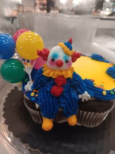 a cupcake decorated like a clown with balloons