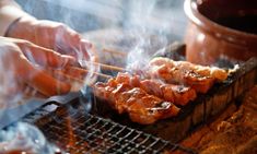 someone is cooking meat on a grill with chopsticks