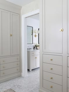 a white bathroom with gold handles and drawers