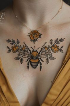 a woman's chest with a bee and roses tattoo on it, as well as an orange rose