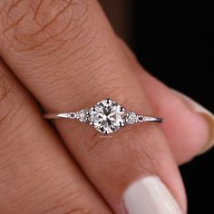 a woman's hand with a diamond ring on her finger and white nail polish