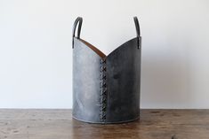 a large metal bucket sitting on top of a wooden table next to a white wall