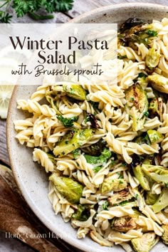 a bowl filled with pasta and brussels sprouts on top of a wooden table