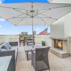 an outdoor patio with chairs, tables and an umbrella over the fire place in front of it