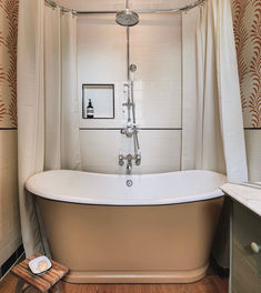 an old fashioned bathtub in a bathroom with wood floors