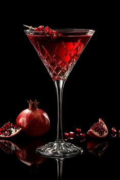 a pomegranate garnish in a martini glass on a reflective surface