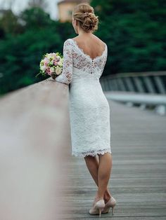 a woman in a white dress is walking on a bridge with her bouquet and shoes