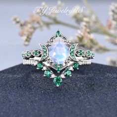 a ring with green and white stones on top of a blue stone table next to flowers