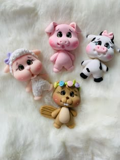 four small toy animals sitting on top of a white fur covered floor next to each other