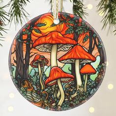 a glass ornament hanging from a christmas tree with orange mushrooms in the background