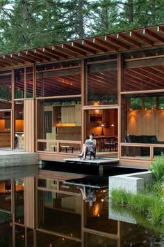 a person sitting on a dock in front of a house that is built into the water