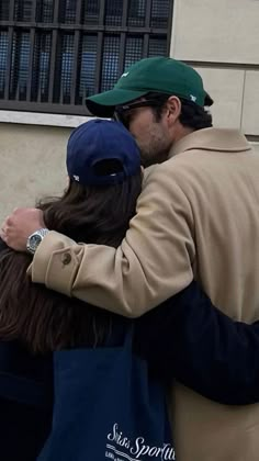 two people embracing each other in front of a building