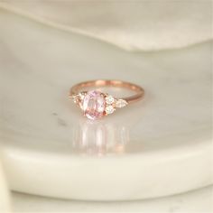 a pink diamond ring sitting on top of a white plate