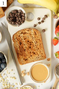 a white tray topped with sliced bread next to bowls of fruit and nuts