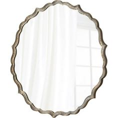 a round mirror hanging on the wall next to a white curtain with a window behind it