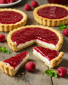 raspberry cheesecake tarts on a wooden table with fresh raspberries