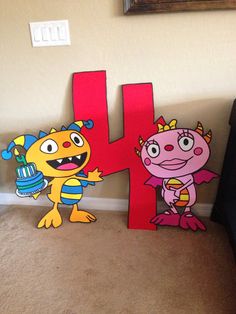 the letter h is made out of cardboard and has cartoon characters on it's sides