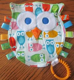 an owl shaped bib with colorful owls on it and a hair clip in the foreground