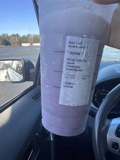 a person is holding a plastic cup in their hand while sitting in the driver's seat