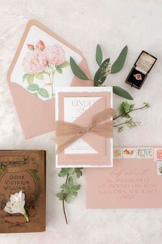 the wedding stationery is laid out on top of each other, including an envelope and ring