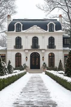 a large white house covered in snow next to trees