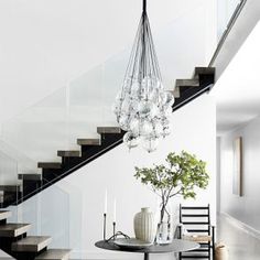 a dining room table sitting under a chandelier next to a stair case with glass balls hanging from it