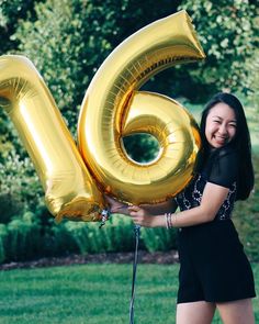 a woman holding up a large number six balloon in her hand and smiling at the camera