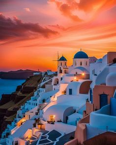 the sun is setting over some white buildings with blue domes on them and water in the background