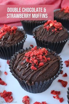 chocolate cupcakes with red sprinkles are on a white plate next to some candy