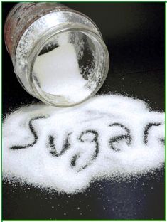 sugar spilled out of a jar on top of the word sugar written in black ink