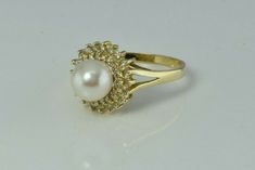 "14K Yellow Gold Pearl and Diamond Halo Ring, 7.5mm white pearl green and pink lustre, 2 rows of diamonds, halo .5\" across ring, Ring size 6.5, Circa 1970, 3.6 grams Stock # BB234R24 Most rings are sizable for a small fee. If the ring you are considering is the incorrect size contact us for a quote. This listing contains photographs of the actual item you will receive. Our items are in excellent condition with little or no signs of wear and many are one of a kind pre-owned estate finds. Please Luxury Formal Pearl Ring With Halo, Formal Round Cut Halo Pearl Ring, Formal Diamond Pearl Ring With Halo, Formal Diamond Halo Pearl Ring, Round Diamond Pearl Ring, Formal Pearl Ring With Diamond Halo Design, Formal Diamond Pearl Ring With Halo Design, Elegant Cluster Halo Ring, Formal Round Pearl Ring With Halo Setting