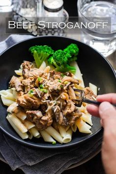 a bowl filled with pasta, meat and broccoli on top of a table