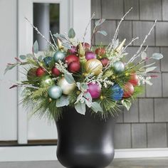 a black vase filled with ornaments and greenery