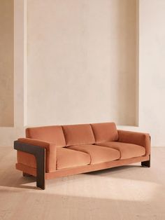 an orange couch sitting on top of a hard wood floor next to a white wall