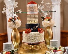 a multi layer cake sitting on top of a table next to two vases filled with flowers