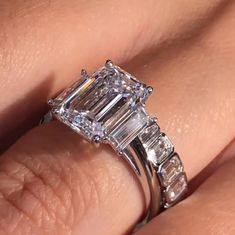 a woman's engagement ring with an emerald and baguettes on the side